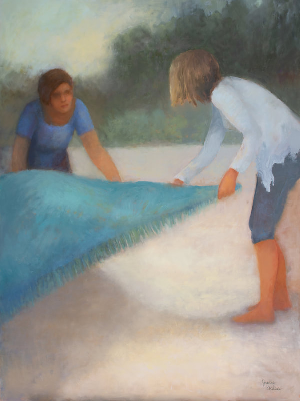 Two women spreading blanket on beach.